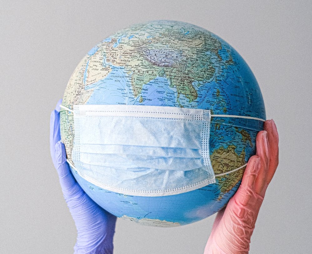 Hands With Latex Gloves Holding a Globe with a Face Mask