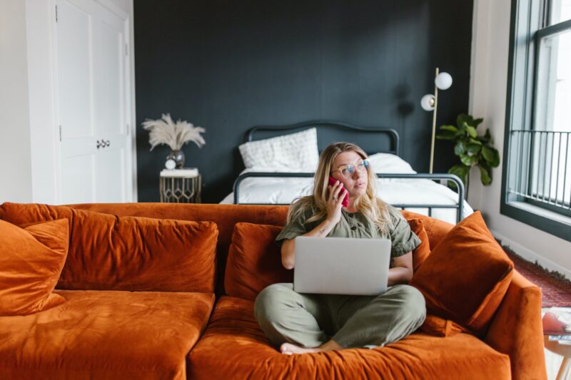 Person with laptop talking on the phone while sitting on the couch