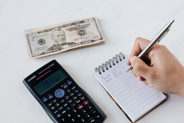 Crop anonymous financier planning budget writing numbers in notebook Crop anonymous financier planning budget writing numbers in notebook