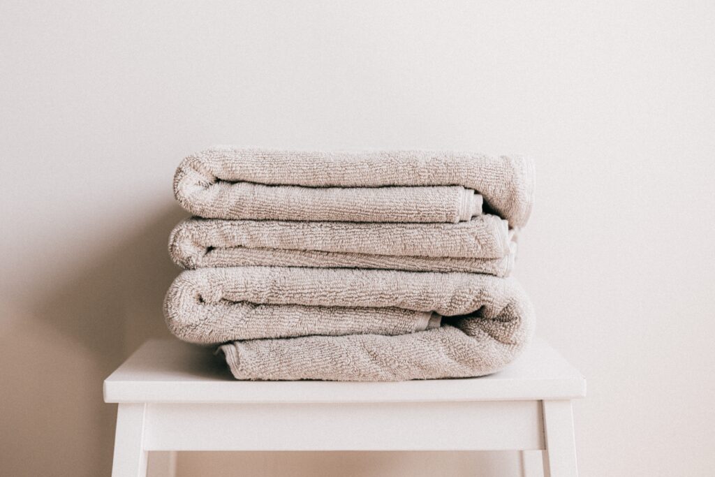 Stack of light beige towels on white stool Stack of light beige towels on white stool