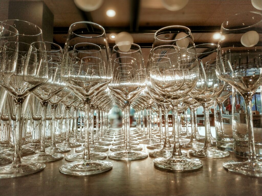 Clear Wine Glasses on Brown Wooden Table Clear Wine Glasses on Brown Wooden Table