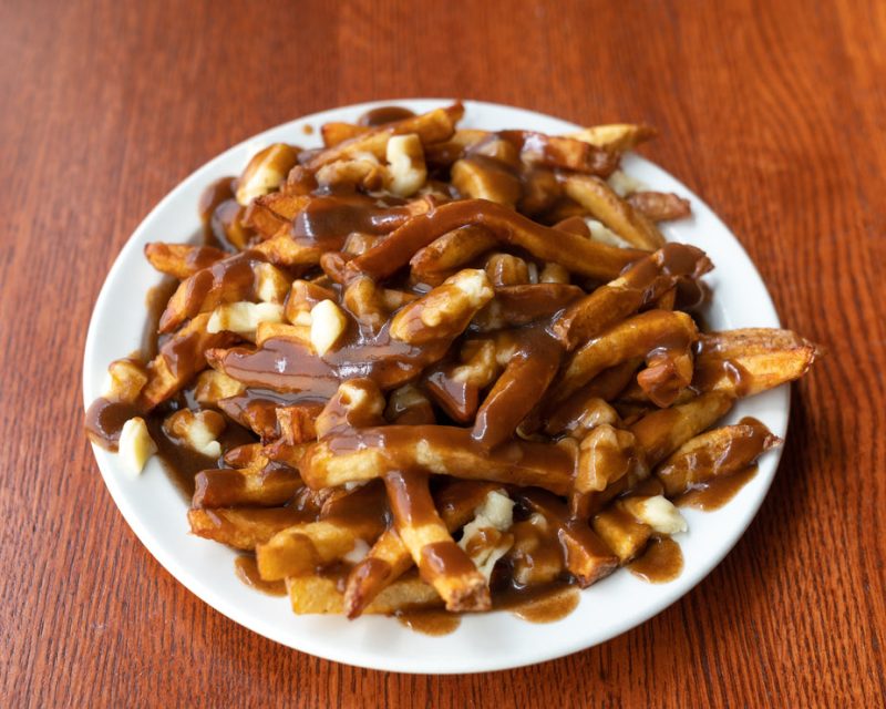 A plate of poutine topped off with cheese curds and thick gravy