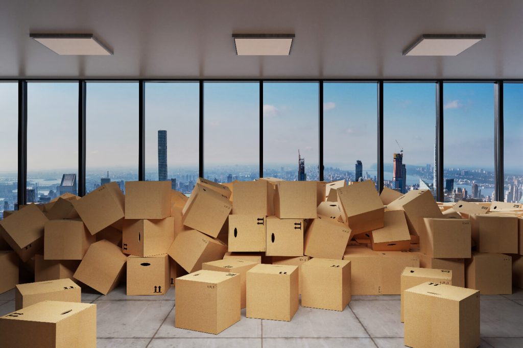 large industrial urban warehouse with large pile of cardboard moving boxes in front of Skyline