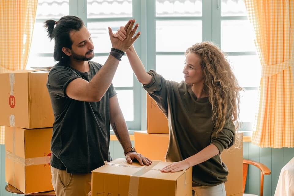 couple high fiving near a pile of moving boxes