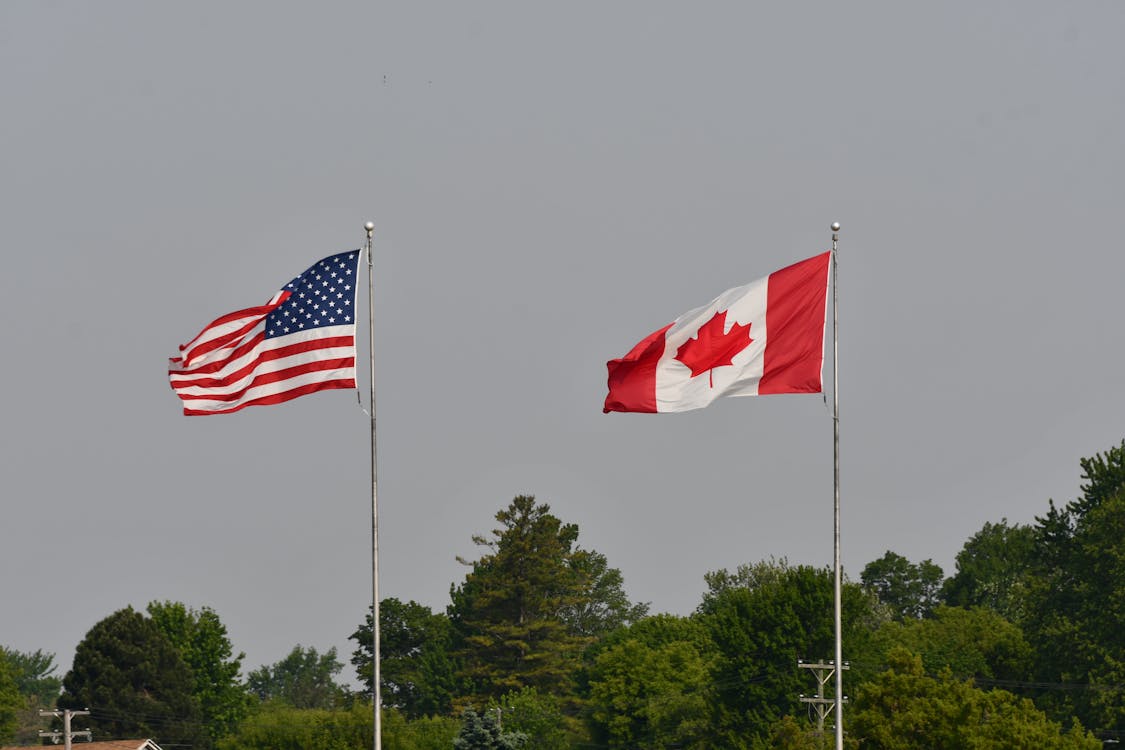 Canadian and American flags flapping in the wind on an overcast day Canadian and American flags flapping in the wind on an overcast day